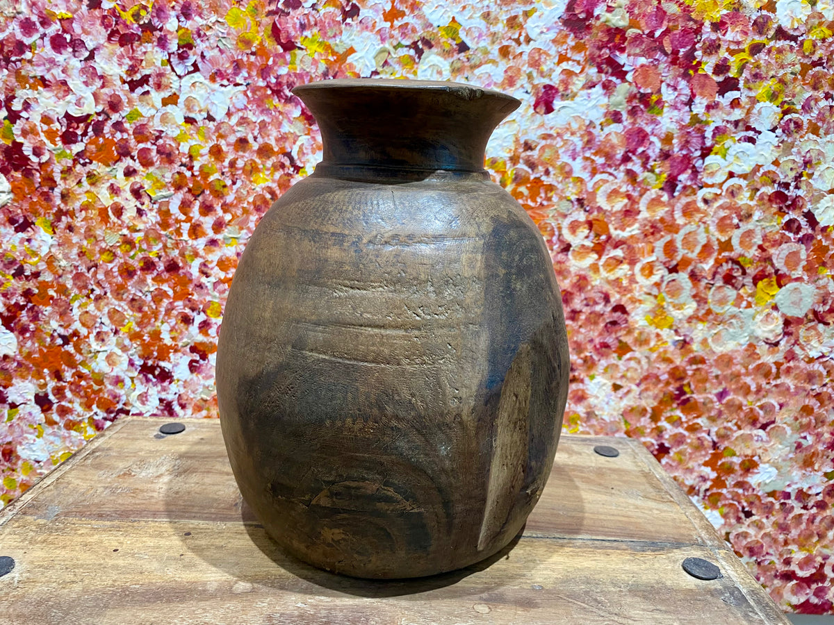 These gracefully shaped pots were used to store lassi, oil, milk, water and grain. This large example comes from northern India and is carved from solid hardwood, in this case most likely teak. Mid 20th century or earlier. slight decoration around the neck and mouth. Repair to the base. Measurements: diameter 22 cm, height 28 cm