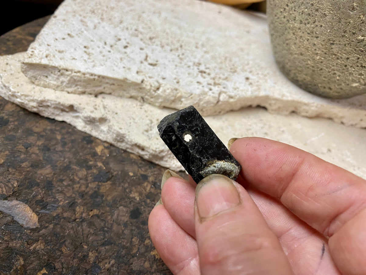 Natural six sided black tourmaline crystal. This has a large hole drilled through the top.  Measurements: 3.3 cm length, width 1.4 x 1.8 cm