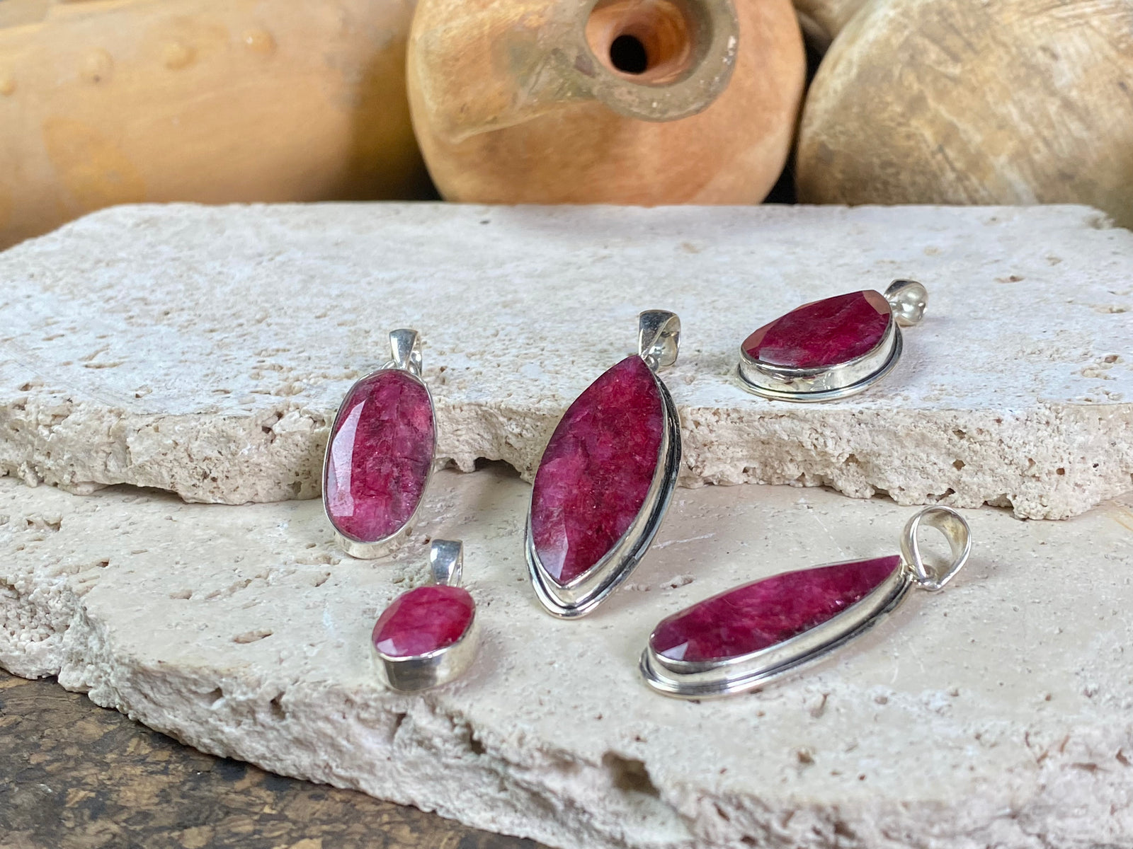 Natural ruby pendants featuring large facet cut stones set in sterling silver. All are set with generous bails to fit on even the largest of chains, torcs or cords. Ranging in length from 6 cm to 2.5 cm