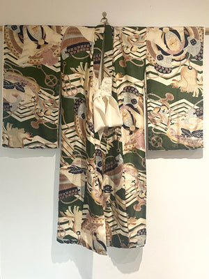 Small, hand sewn child's kimono suitable for either sex. A tasteful design features greens, tans, navy, lilac and pale blue colours in an abstracted design reminiscent of its era. Padded and lined. Hand stitched silk ties with fine thread tassel detailing. No damage, excellent condition. Circa 1950's.