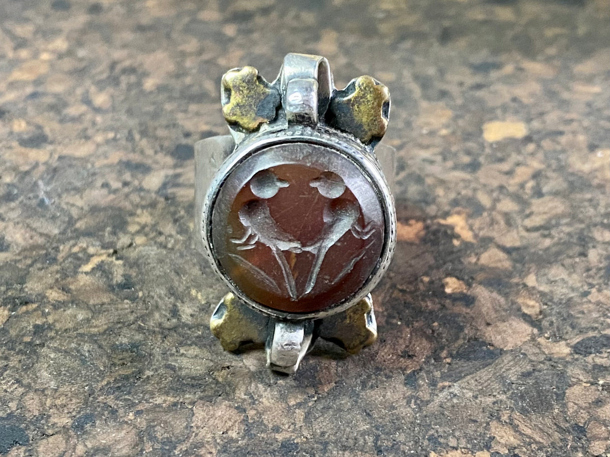 Afghani ring features a large carnelian stone carved with the images of two birds. Medallions of brass, silver loops and an embossed band complete the decoration. This large silver ring sits high on the finger and is statement jewellery. Adjustable ring, inner diameter 18 mm | Size 7.75 | No 17