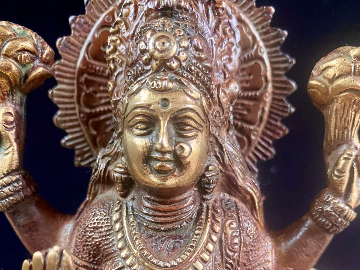 A statue of the goddess Laxmi (or Lakshmi), Hindu goddess of wealth and prosperity. Cast from solid brass, her features are exquisitely detailed, while her face, hands and feet are polished. Her right hand is raised in the gesture of protection and her left hand holds a pot symbolising abundance. Measurements: 19.8 cm height, width12 cm, depth 8.3 cm