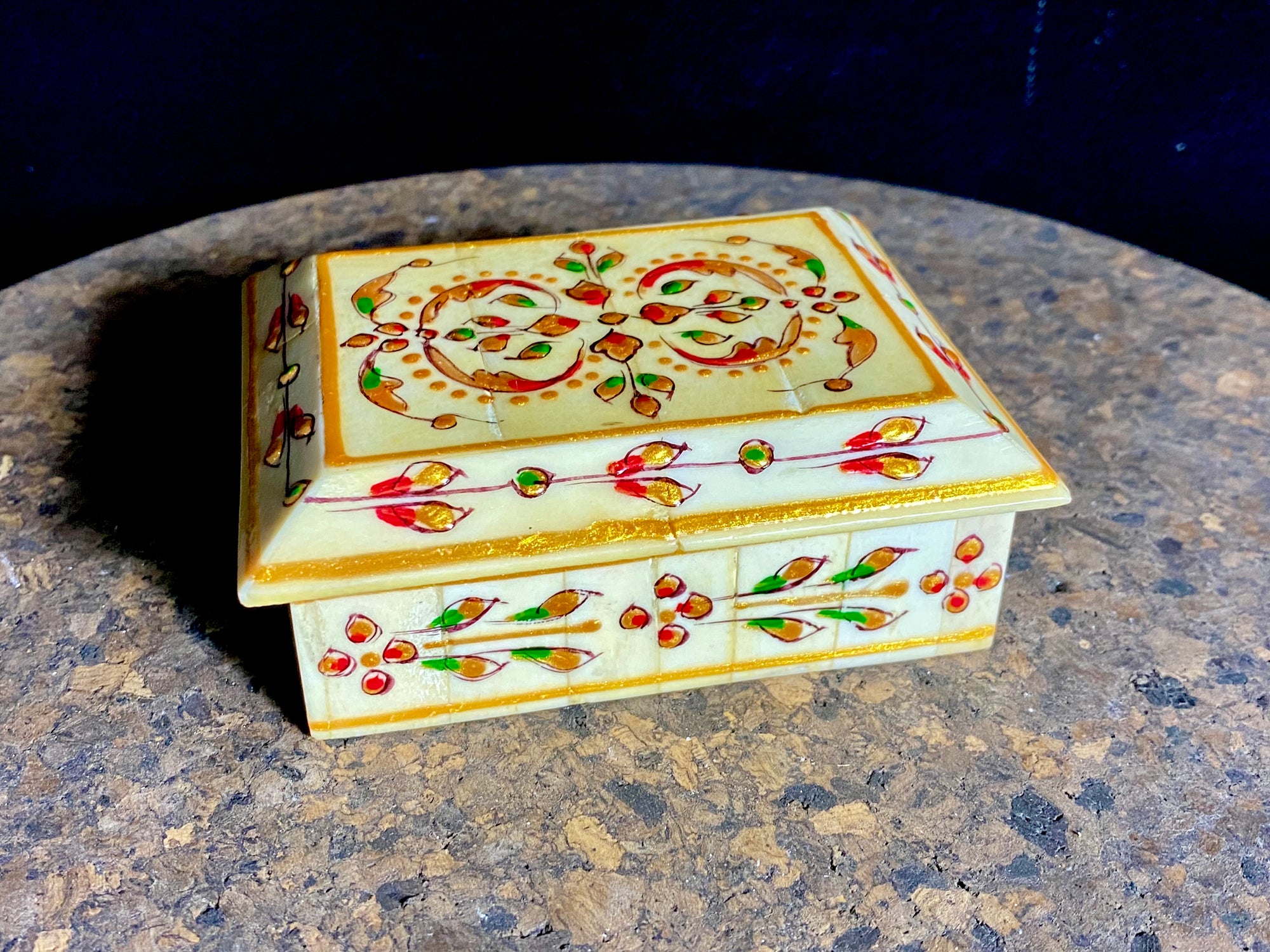 A compact trinket box, hand crafted from wood overlaid with polished hand shaped panels of camel bone, which are then exquisitely hand painted.  Measurements: 10 cm x 7.5 cm, height 4 cm 