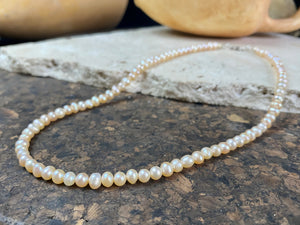 A simple pearl choker necklace, featuring champagne coloured off-round pearls, finished with sterling silver findings and clasp.  These are quality cultured freshwater pearls with a beautiful sheen and thick nacre finish.   Measurements: length 39.5 cm including clasp. Pearls are 4 mm diameter