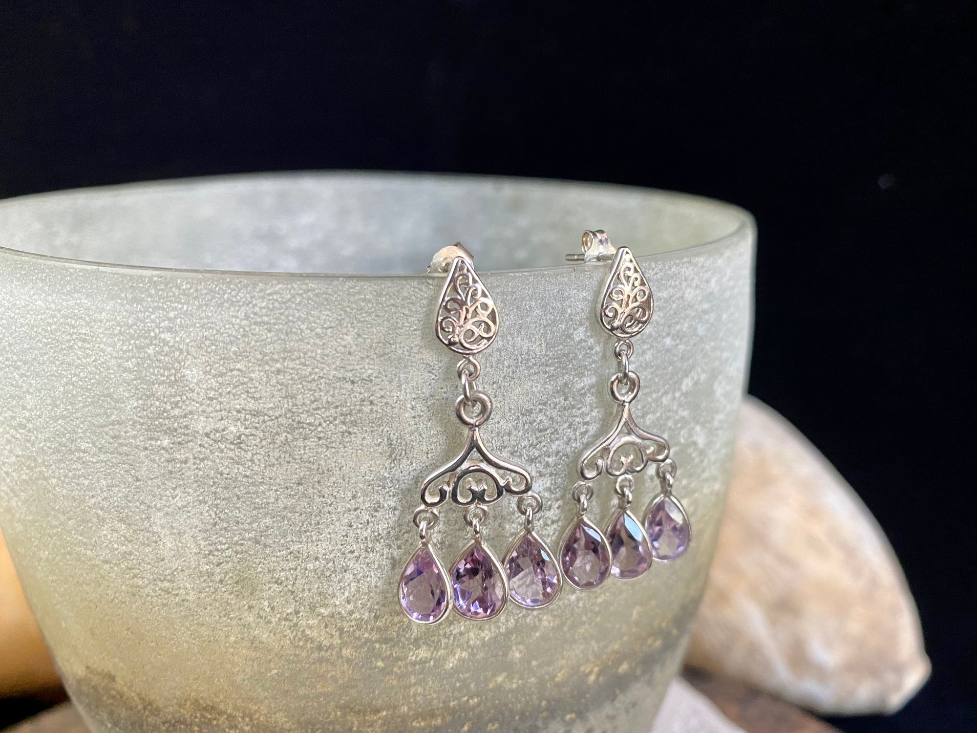 Amethyst chandelier earrings set in filigree silver with a post and butterfly back attachment. The matching light purple teardrop shape amethyst stones are facet cut to display their excellent quality and sparkle as they move en tremblant.