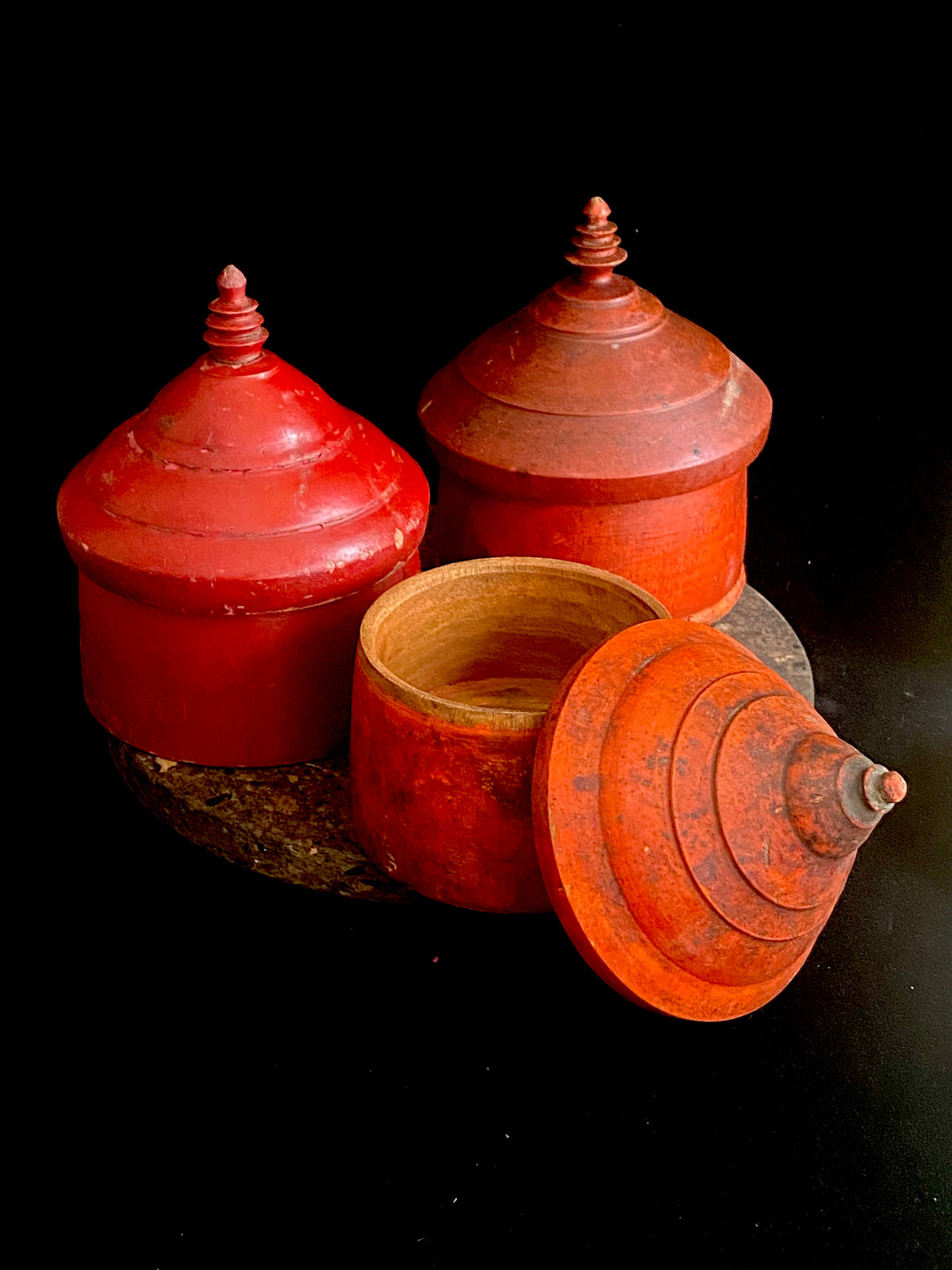 Large red lacquered tikka pot or tikka boxes. Hand carved from single hollowed out pieces of teak, these lidded pots traditionally hold the red vermillion (bindi) powder used for marking the forehead during Hindu ceremonies. They date to the early 1900s. Measurements: approximate diameter 12-14 cm, height 16-18 cm 