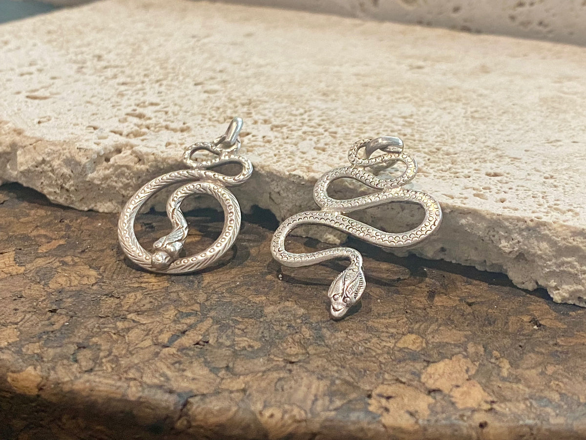 Hand cast snake pendants. Two styles. Sterling silver. Set with a wide bail capable of taking a sizeable chain or cord. Our unisex snake pendants are from Nepal.&nbsp;