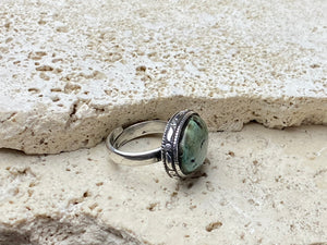 This simple ring features a large antique cabochon turquoise stone, set in a simple patterned silver bezel, with an adjustable ring band. As is the case with many of the rings we are currently buying, the stone is old and has been reset into a new silver band.  Measurements:  Ring face 2 x 1.5 cm Inner diameter 16.5 mm | Size 6 , however the adjustable band will fit any finger sized 5 -7