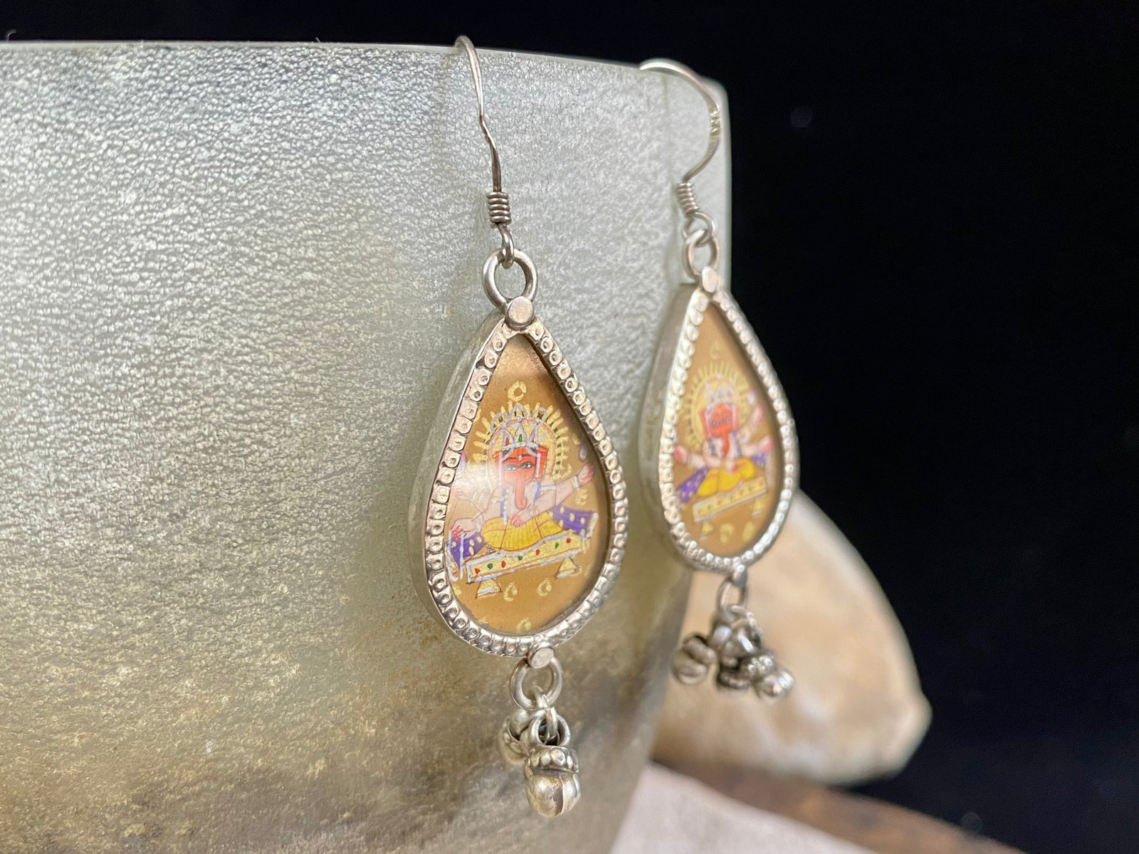 Exquisite miniature hand painted earrings featuring Ganesh seated, set within sterling silver frames, backed with decorated silver and set with a silver dangles bail at the base.  Bought from the artist who painted them in India, then set into silver.  Measurements: 6 cm (2.35") height including hooks or 2 cm at widest point