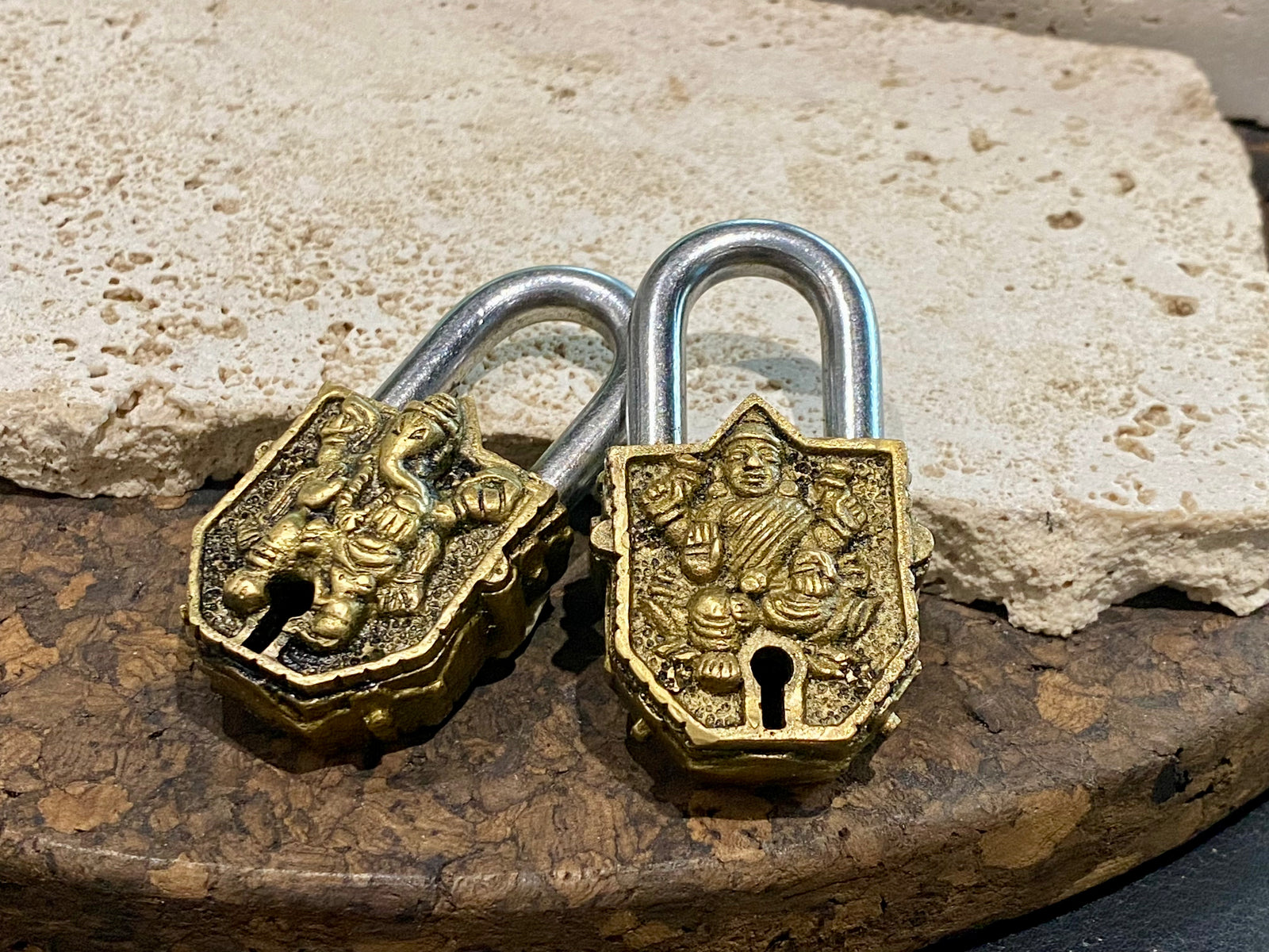 Small brass Indian deity padlocks embossed with the image of Ganesh or Laxmi. to keep your possessions safe and blessed. On the back is the Om, powerful Buddhist protective symbol. Two keys provided with every lock. On the top of each is the viswa vajra, a Buddhist protective symbol. Measurements: height 6.5 cm, width 3 cm, depth 1.5 cm