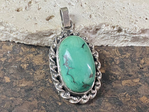 Arizona turquoise pendant set off by a detailed sterling silver bezel, with an enclosed silver back, topped by a large bail large. Measurements: 4.6 cm height including bail, width 2.2 cm