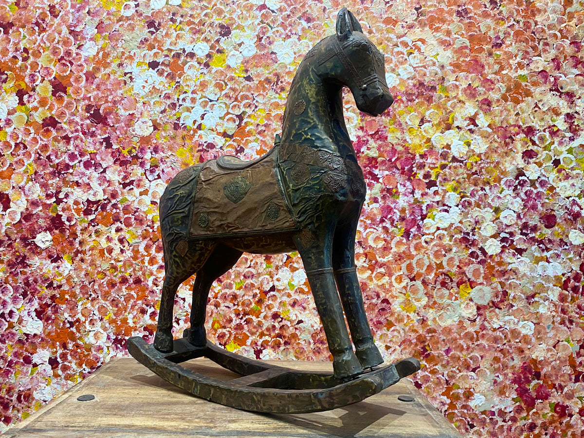 Antique Indian rocking horse. Covered entirely in sheets of embossed brass and copper sheet with floral and ornamental plaques, strap work and highly embossed decoration. Hardwood Early 20th century, southern India. Measurements: height to ear 52 cm, length 40.5 cm, width 13.5 cm.