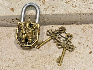 Small brass Indian deity padlocks embossed with the image of Ganesh or Laxmi. to keep your possessions safe and blessed. On the back is the Om, powerful Buddhist protective symbol. Two keys provided with every lock. On the top of each is the viswa vajra, a Buddhist protective symbol. Measurements: height 6.5 cm, width 3 cm, depth 1.5 cm