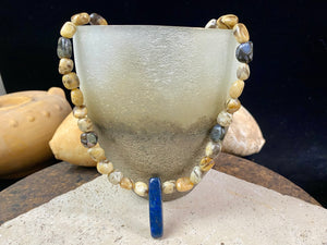 A necklace crafted from zebradorite  jasper with highlight beads of grey opal and a central hand carved pendant of Afghani lapis lazuli. Finished with sterling silver beads and hook clasp. Our necklace can be worn by either men or women  Length 42.4 cm 