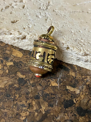 Miniature prayer wheel or prayer box designed to be worn as a pendant, a charm on a bracelet or added to a keyring. Brass and copper, containing a prayer scroll. Height 3 cm. Mantra is Om Mani Padme Hum, prayer to the Compassionate Buddha