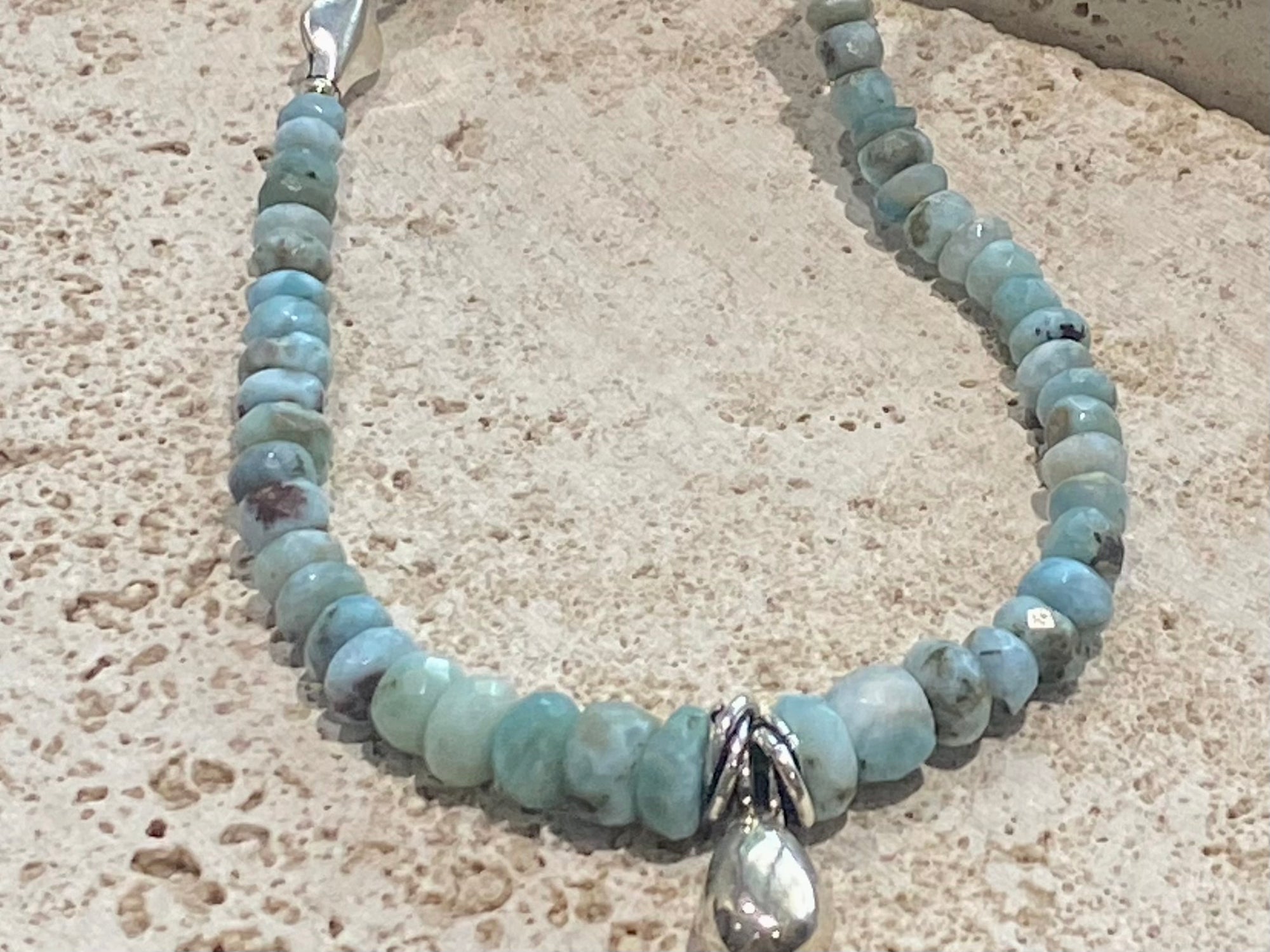 Light blue blue necklace of tumbled, facet cut graduated larimar, highlighted with Rajasthani silver beads and a beautiful central drop pendant. Finished with sterling silver findings and hook clasp. and a hook clasp. Measurements: 46 cm (18") length