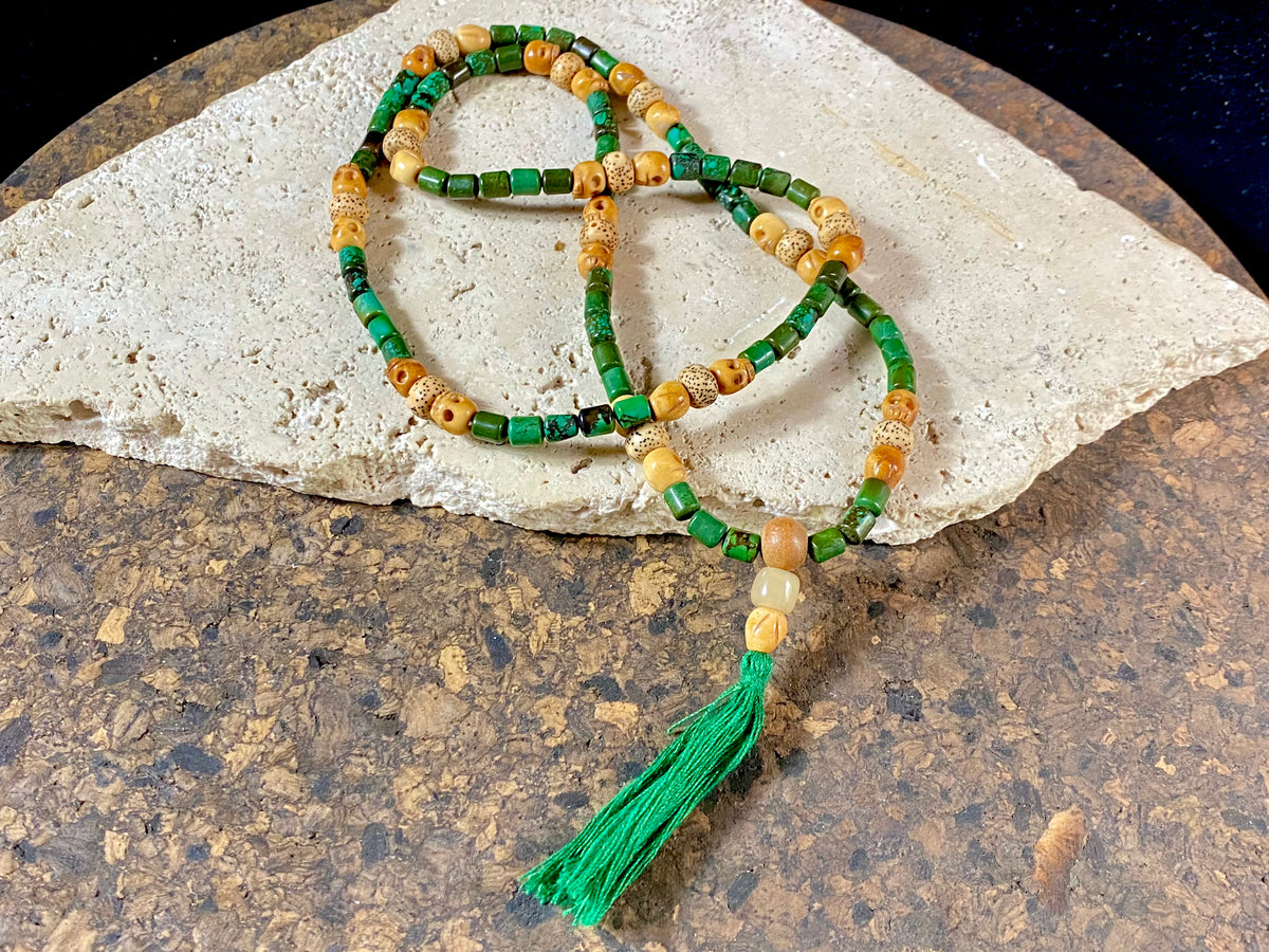 Our luxurious Buddhist mala contains 108 beads and has a beautifully organic look and feel. It's made from dark green turquoise beads, skull carved yak bone beads and lotus root beads, all finished with a sandalwood guru bead and a yak horn bead. Finished with a dark green tassel.