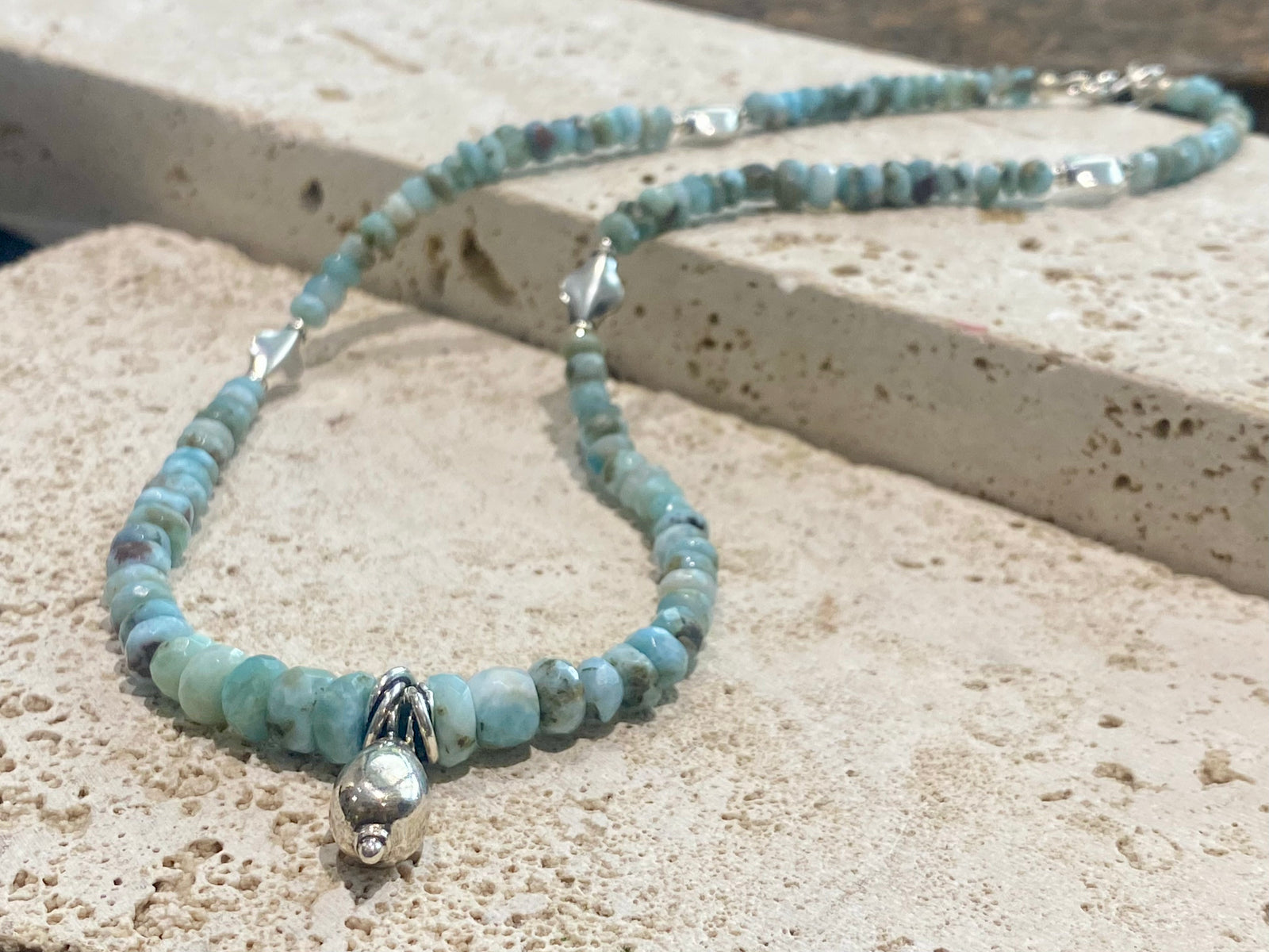 Light blue blue necklace of tumbled, facet cut graduated larimar, highlighted with Rajasthani silver beads and a beautiful central drop pendant. Finished with sterling silver findings and hook clasp. and a hook clasp. Measurements: 46 cm (18") length