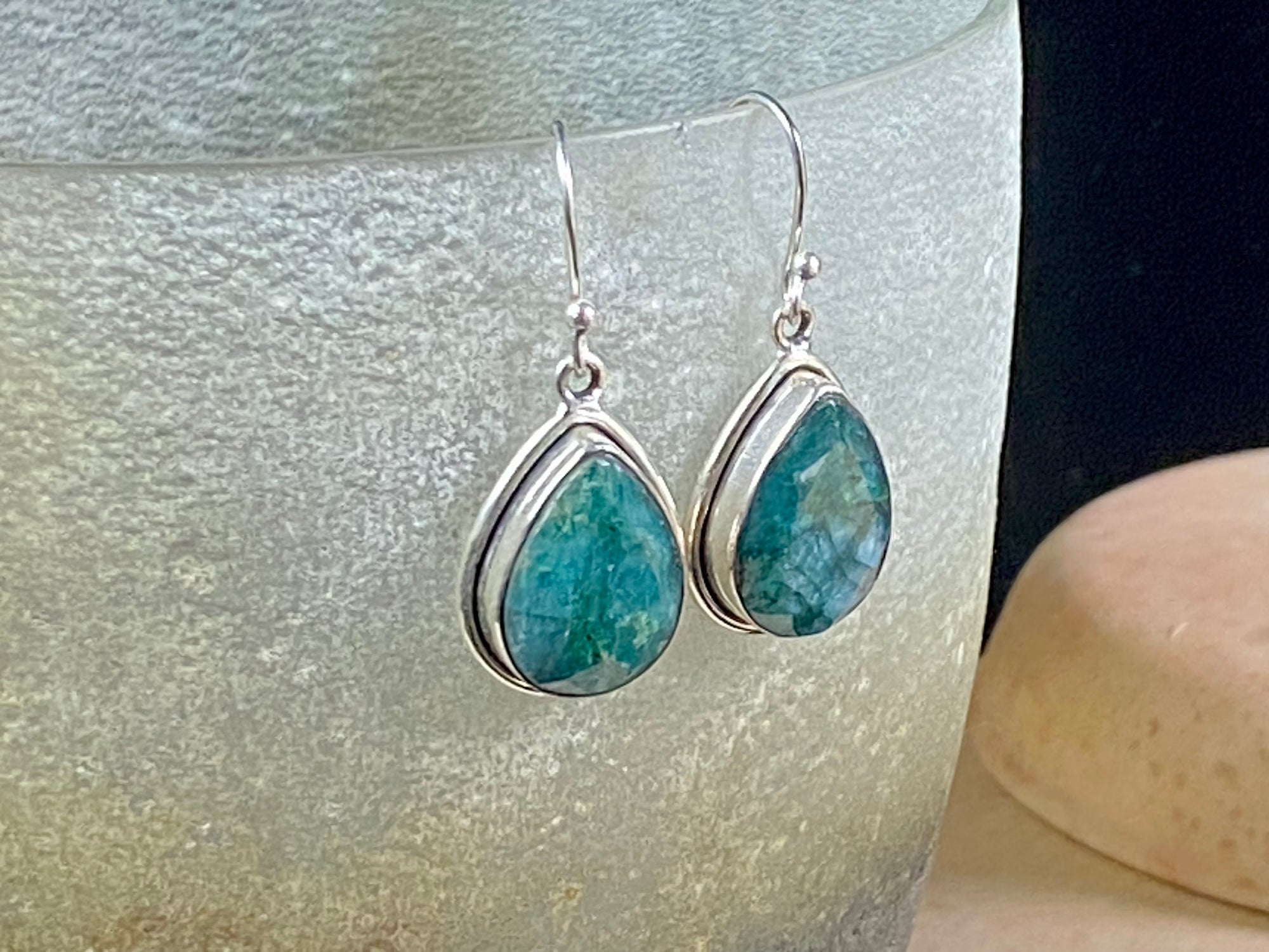 Our beautiful teardrop emerald earrings feature large facet cut emeralds of a deep variegated green colour. They are set in a sterling silver shadow box mount to highlight their beauty. measurements 3.6 cm length including hook.