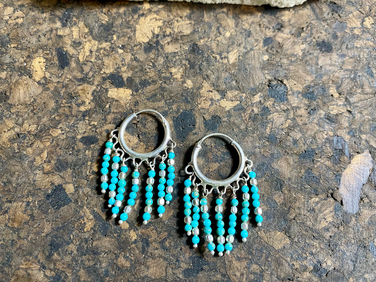 Our handmade fringed southwest-style turquoise earrings are crafted from Sleeping Beauty turquoise and handmade silver bead detailing. Sterling silver hoops complete the look. These earrings are designed to sit with the fringe facing parallel to the face. Measurements: Length 3.7 cm, 2 cm diameter