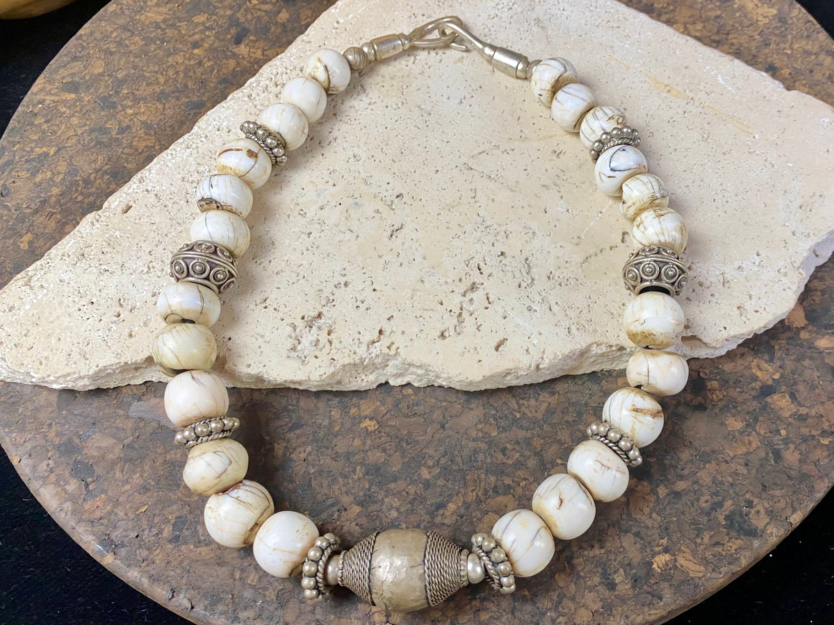 This statement choker necklace inspires Boho chic and features large antique Naga shell beads beads, vintage Indian silver beads and a handmade sterling silver hook. The central bead is an old piece consisting of hand wrapped silver over a wood frame. Length 48 cm