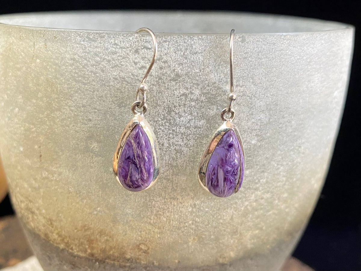 These lustrous charoite earrings are set off by a sterling silver bezel, topped by sterling silver shepherd hooks.  Measurements: 3.5 cm height including hooks, 1 cm at widest point 