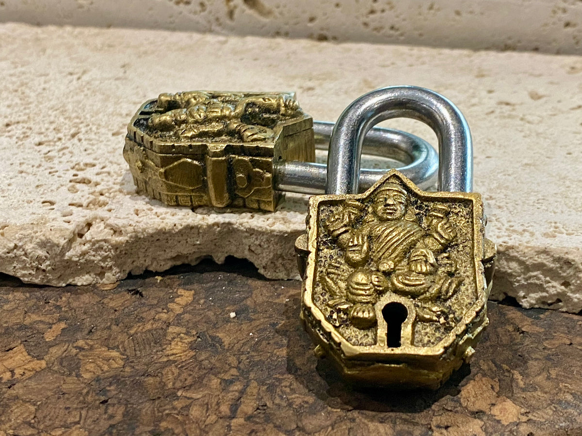 Small brass Indian deity padlocks embossed with the image of Ganesh or Laxmi. to keep your possessions safe and blessed. On the back is the Om, powerful Buddhist protective symbol. Two keys provided with every lock. On the top of each is the viswa vajra, a Buddhist protective symbol. Measurements: height 6.5 cm, width 3 cm, depth 1.5 cm