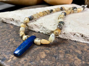 A necklace crafted from zebradorite  jasper with highlight beads of grey opal and a central hand carved pendant of Afghani lapis lazuli. Finished with sterling silver beads and hook clasp. Our necklace can be worn by either men or women  Length 42.4 cm 