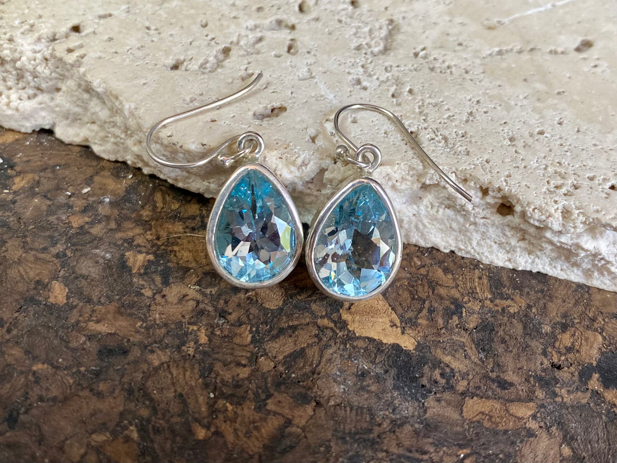 Blue topaz earrings. Deep teardrop cut stones are set in simple silver surrounds and finished with a shepherd hook. The topazes are facet cut to display their excellent quality and sparkle. Measurements: 3 cm height including hook, width 1.1 cm at widest point
