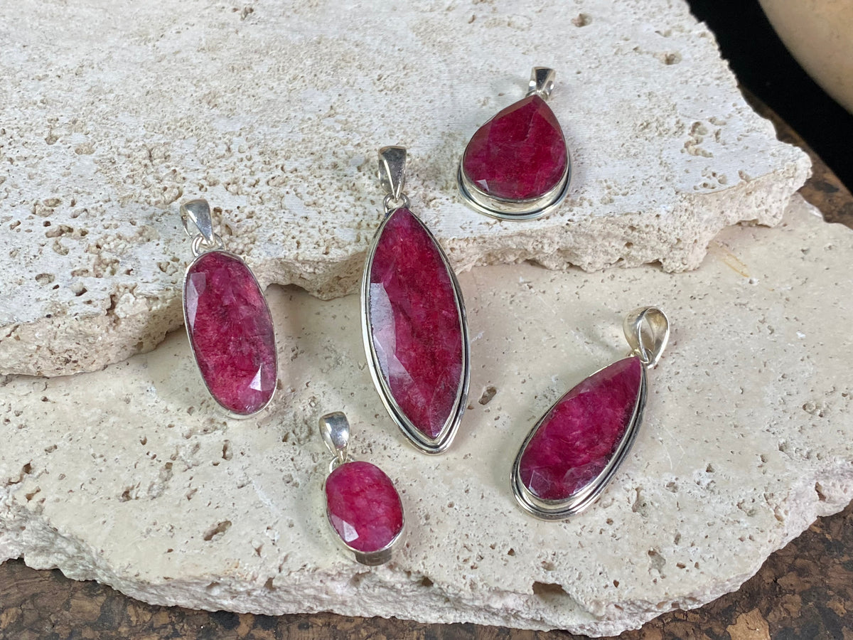 Natural ruby pendants featuring large facet cut stones set in sterling silver. All are set with generous bails to fit on even the largest of chains, torcs or cords. Ranging in length from 6 cm to 2.5 cm