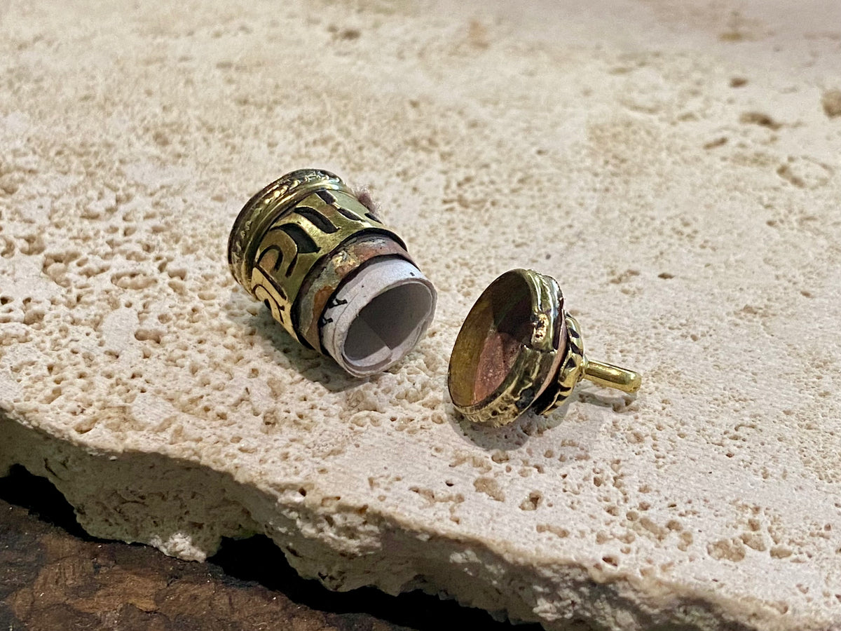Miniature prayer wheel or prayer box designed to be worn as a pendant, a charm on a bracelet or added to a keyring. Brass and copper, containing a prayer scroll. Height 3 cm. Mantra is Om Mani Padme Hum, prayer to the Compassionate Buddha