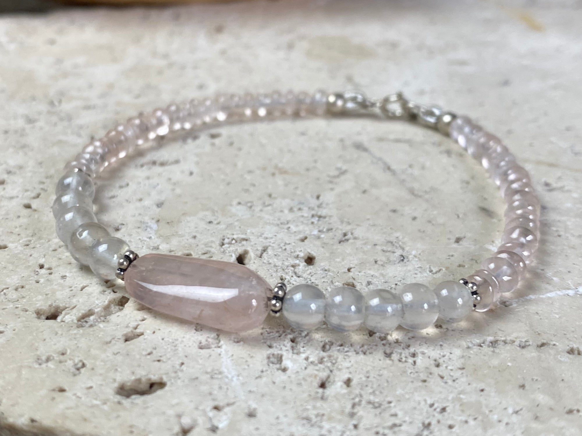 A simple bracelet made from rose quartz, finished with sterling silver detailing and clasp.  Measurements: 19 cm length, centre rose quarrz stone 2 cm length