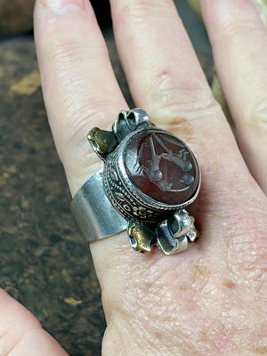 Afghani ring features a large carnelian stone carved with the images of two birds. Medallions of brass, silver loops and an embossed band complete the decoration. This large silver ring sits high on the finger and is statement jewellery. Adjustable ring, inner diameter 18 mm | Size 7.75 | No 17