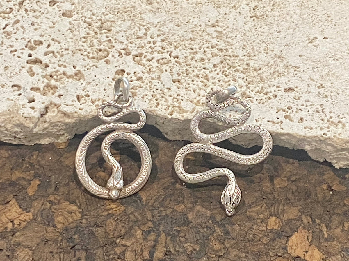 Hand cast snake pendants. Two styles. Sterling silver. Set with a wide bail capable of taking a sizeable chain or cord. Our unisex snake pendants are from Nepal.&nbsp;