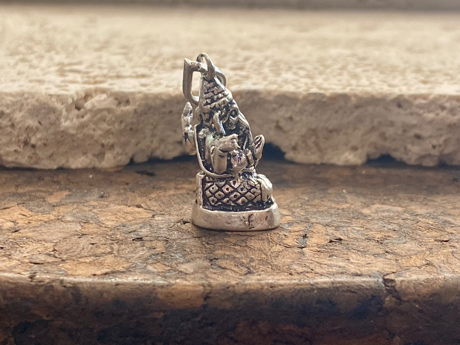 Sterling silver pendant featuring Lord Ganesha portrayed in 3D, this heavy silver charm pendant can be viewed in 3 dimensions, with his back as complete and as detailed as his front. A generous bail allows this pendant to be worn on a large chain or cord. he can even sit upright as the smallest of ganesh statues. This is a unisex pendant or statue. Sterling silver. Measurements: 3 cm height including bail