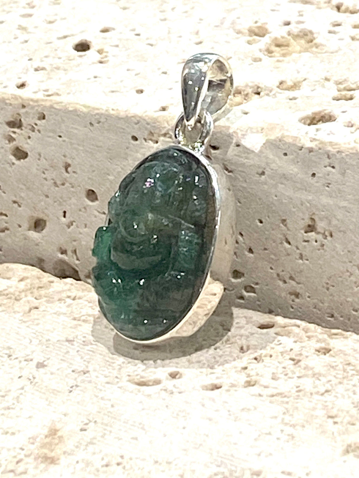 Hand carved from a single high quality translucent emerald and set in a silver surround with silver bail, this oval pendant features a beautifully detailed image of Ganesh.  Height including bail 3.1 cm, width 1.4 cm