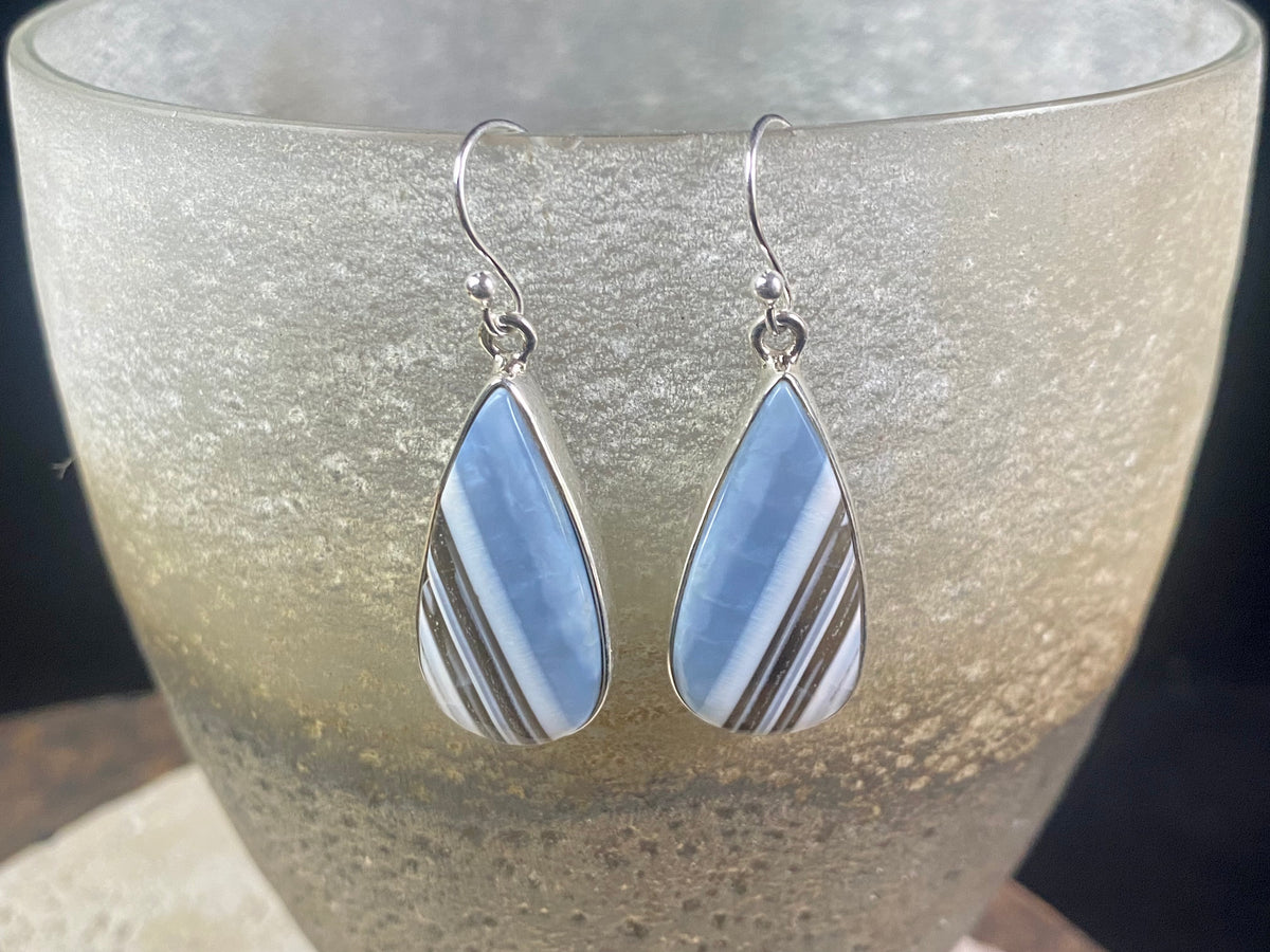 Our stunning earrings feature perfectly matched banded blue opal stones set in sterling silver bezels. Finished with sterling silver hooks.   