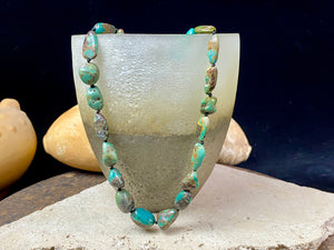A necklace crafted from blue-green Tibetan turquoise, knotted between each bead in the traditional jewellery making technique of the region. Finished with sterling silver beads and hook clasp. Length 42 cm