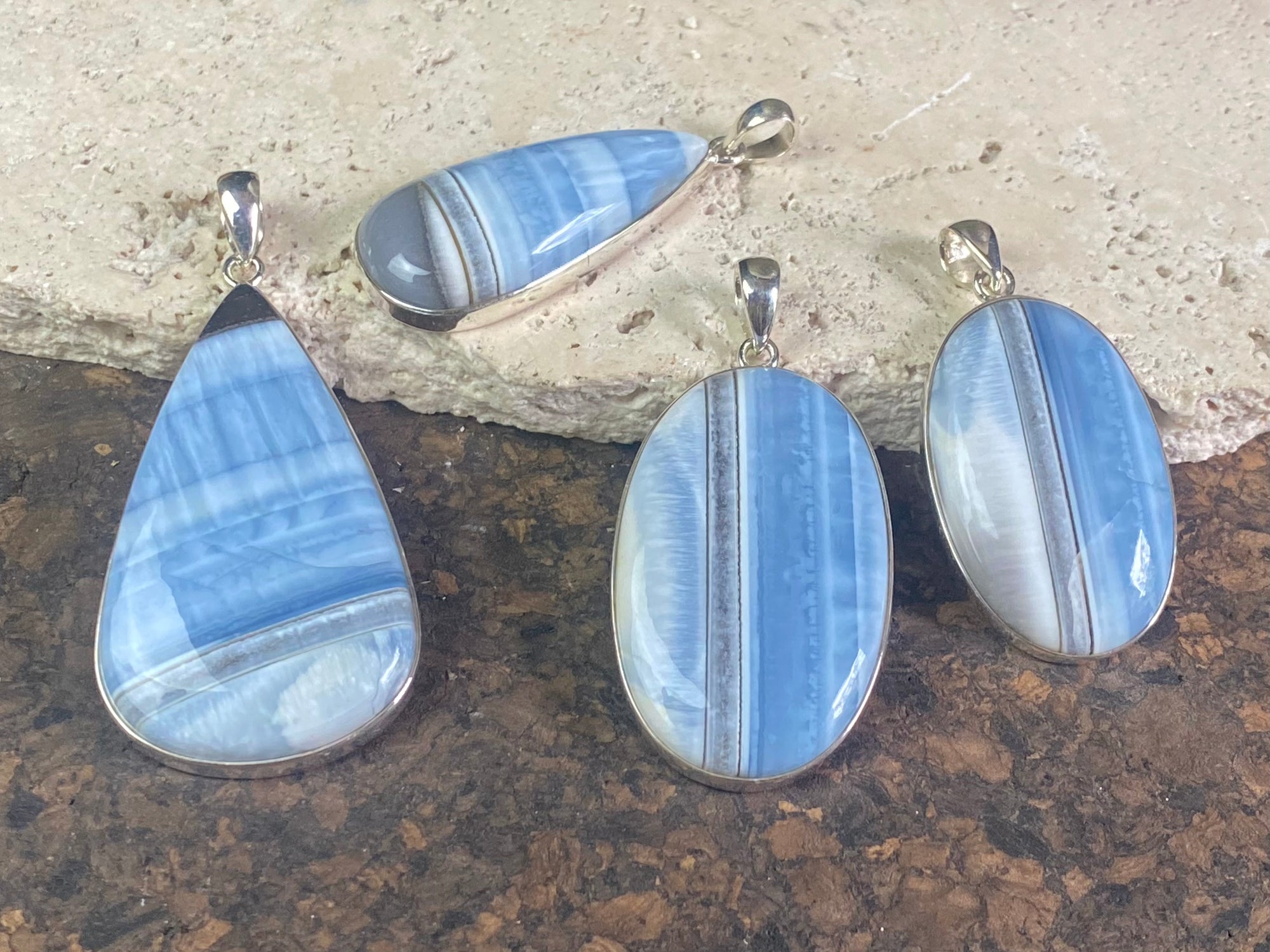 Natural banded blue opal pendants. Set off by sterling silver bezels, topped by generous sized bails large enough to accommodate a thick chain or cord. If you're looking for something a little bit different, this is statement jewellery at its finest.