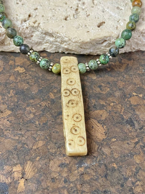 Tribal inspired necklace made from African jasper, highlighted with an antique Naga bone pendant and Kachin antique bone beads. Sterling silver findings and hook clasp. This unisex necklace is 45.5 cm (18") in length, pendant 5 cm (2") length.