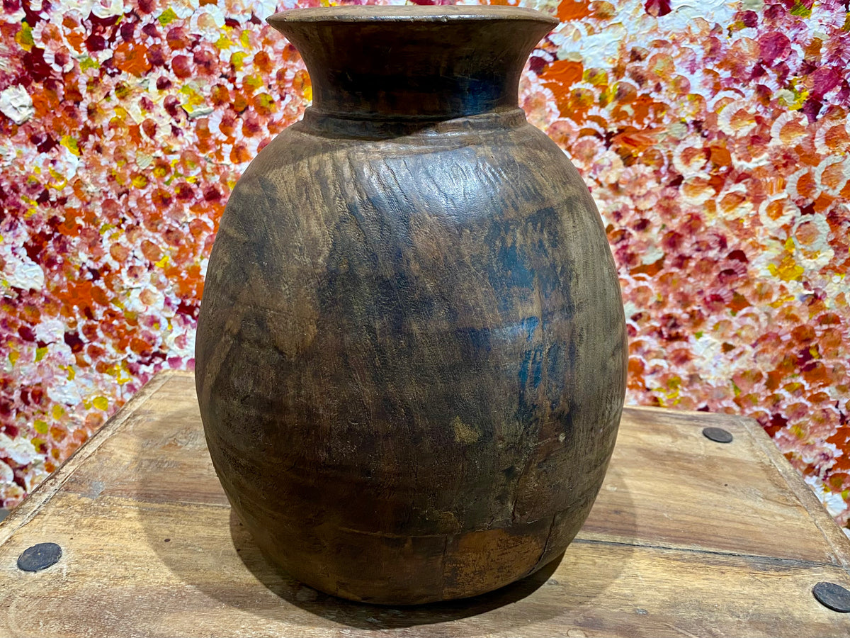 These gracefully shaped pots were used to store lassi, oil, milk, water and grain. This large example comes from northern India and is carved from solid hardwood, in this case most likely teak. Mid 20th century or earlier. slight decoration around the neck and mouth. Repair to the base. Measurements: diameter 22 cm, height 28 cm