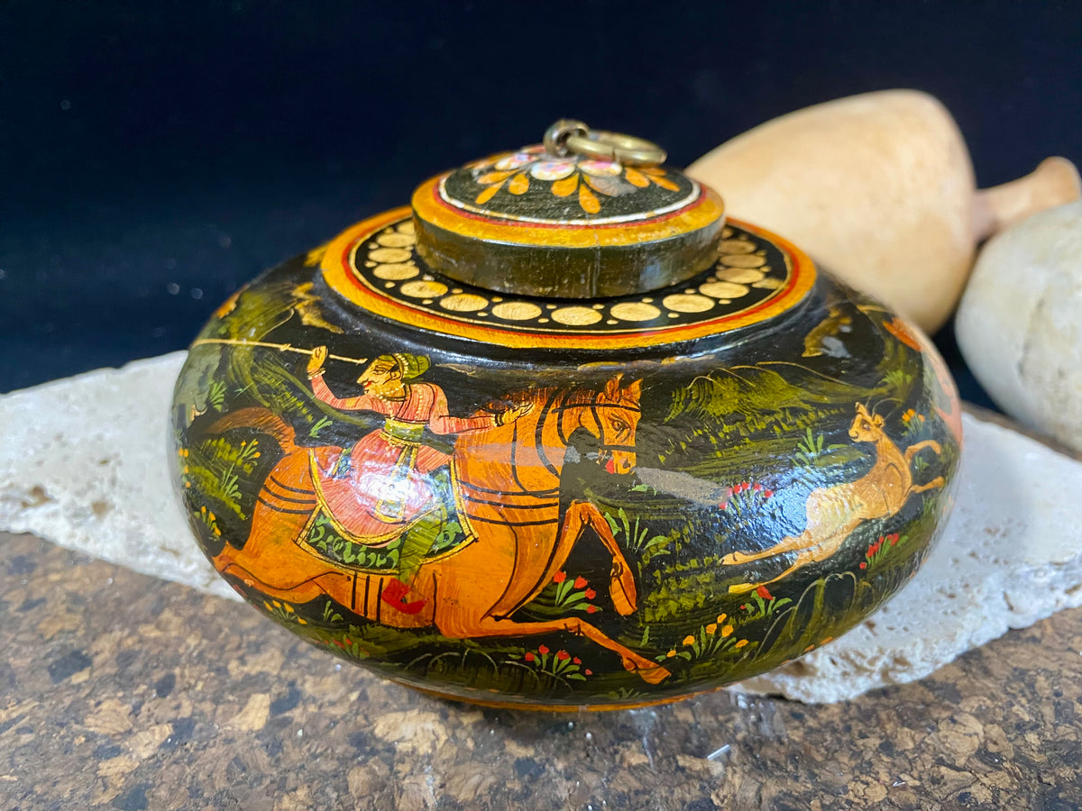 A beautiful low oval lidded bowl or box, traditionally called an opium pot because of its shape. Crafted from wood, then hand painted with hunting scenes. Hand made in Rajasthan, India. Measurements: diameter 14.5 cm, height 7 cm.