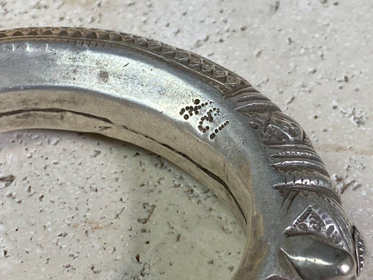 An antique silver cuff, with the ends shaped into the image of a lion's head. Circa early 1900's or earlier, high grade silver. Rajasthan or Himachal Pradesh, India. It has what is most likely the owners mark or initials engraved on it.