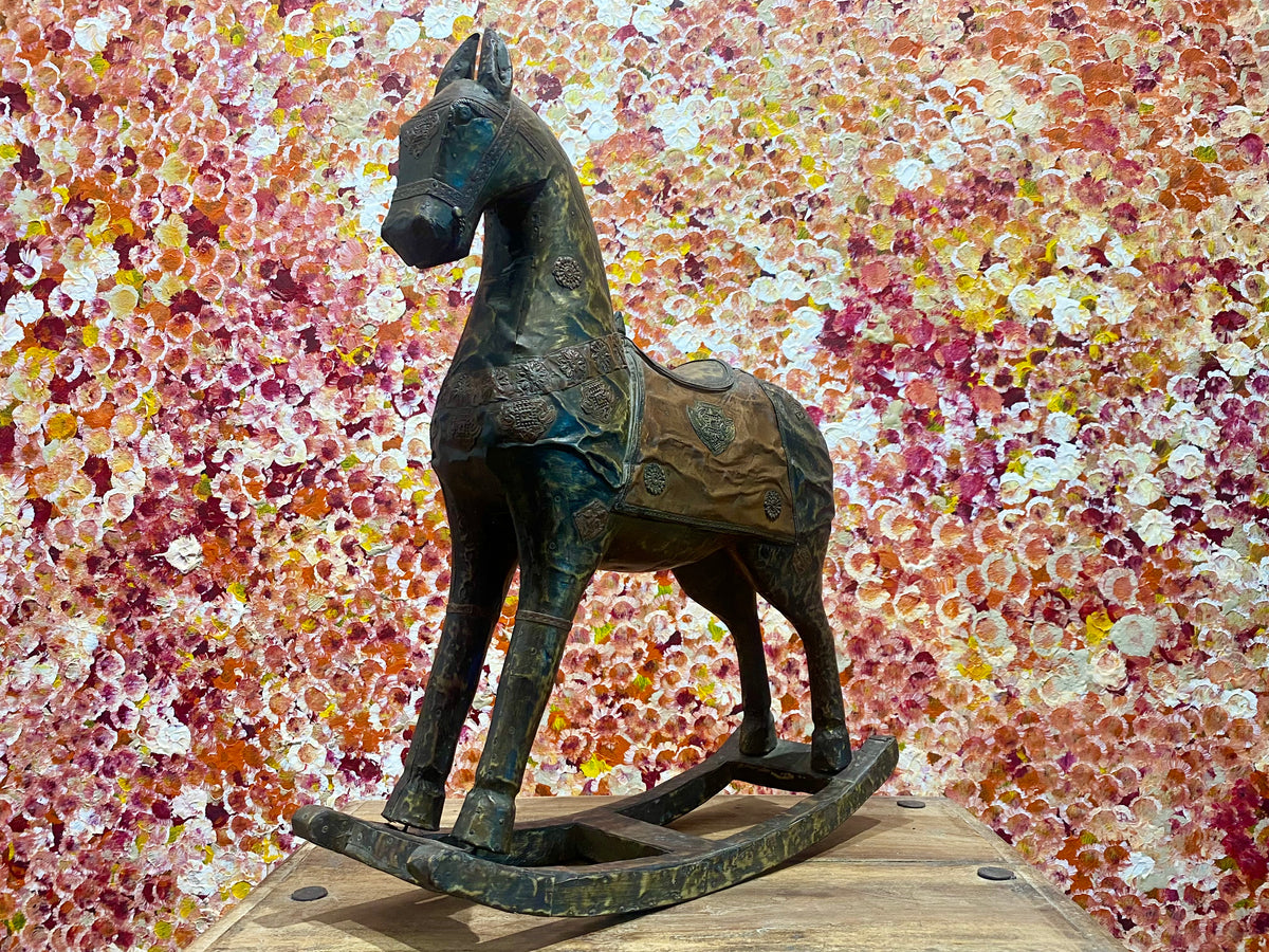 Antique Indian rocking horse. Covered entirely in sheets of embossed brass and copper sheet with floral and ornamental plaques, strap work and highly embossed decoration. Hardwood Early 20th century, southern India. Measurements: height to ear 52 cm, length 40.5 cm, width 13.5 cm.
