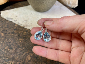 Blue topaz earrings. Deep teardrop cut stones are set in simple silver surrounds and finished with a shepherd hook. The topazes are facet cut to display their excellent quality and sparkle. Measurements: 3 cm height including hook, width 1.1 cm at widest point