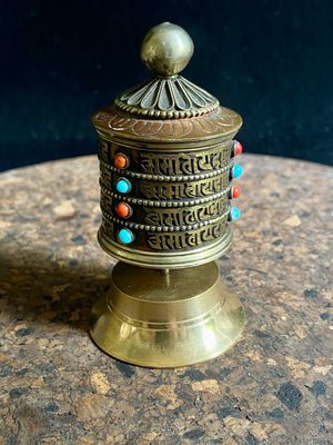 Handmade in Nepal from brass and copper, these small standing prayer wheel are weighted for spinning and contain a scroll on which is printed the mantra "Om Mani Padme Hum", a prayer to the Compassionate Buddha, written many times over. Two styles.  Measurements: height 9 cm