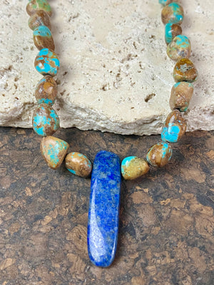 Our necklace is crafted from Tibetan turquoise with a central hand carved pendant of lapis lazuli. Finished with sterling silver beads and hook clasp. These beautiful natural stones range in colour from blue to blue-green. Length 42 cm