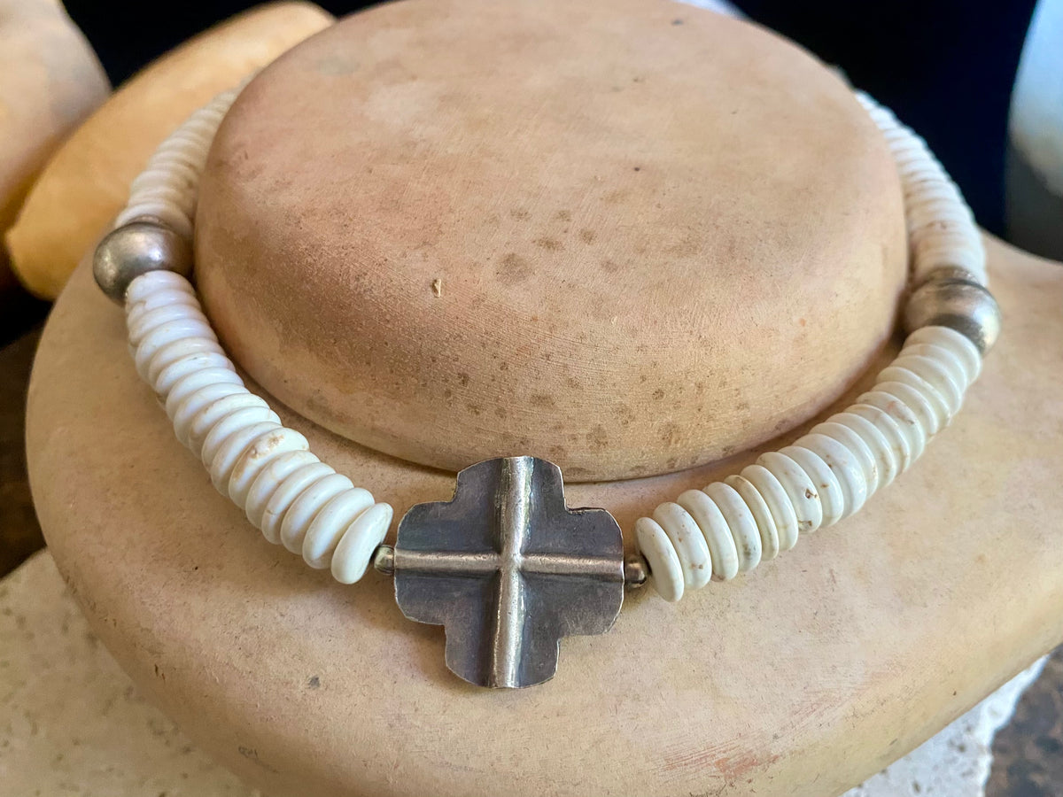 A mid-length white howlite and silver necklace crafted crafted from natural heshi cut beads, with a handmade sterling silver cross centrepiece and antique Indian silver beads. Finished with sterling silver ends and hook clasp. Total length 51.8 cm, pendant 2.5 cm diameter