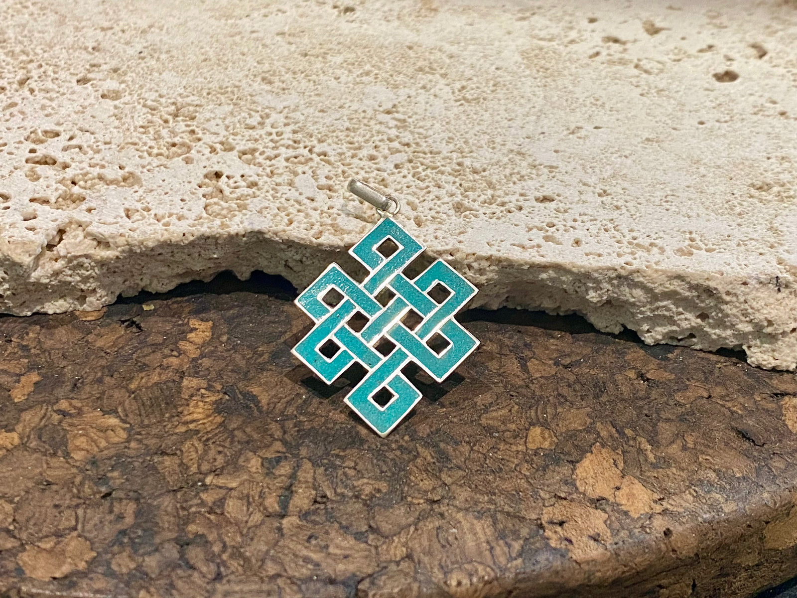 Sterling silver and turquoise Endless Knot pendant, one of the eight auspicious symbols of Buddhism. Sterling silver, set with ground chips of turquoise in enamel, from Nepal. Height 4 cm including bail