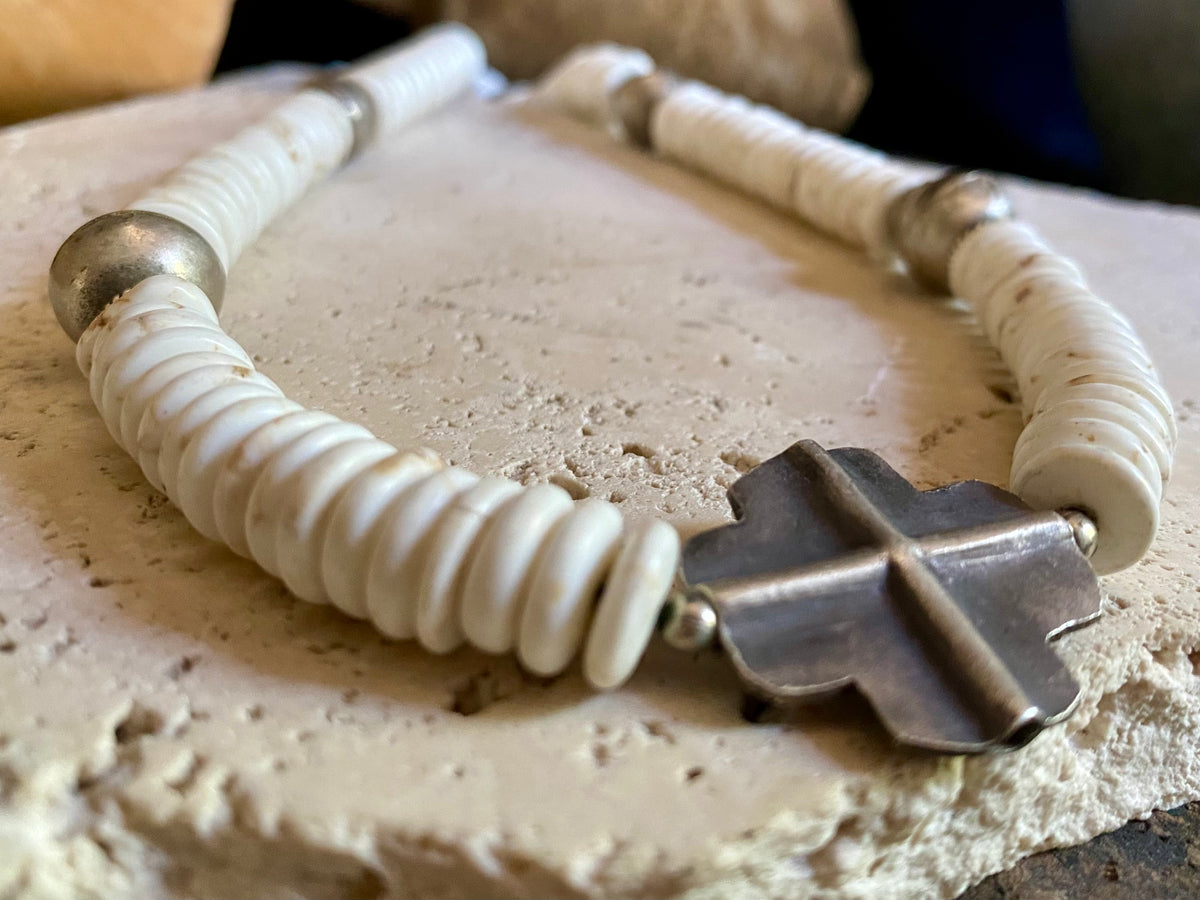 A mid-length white howlite and silver necklace crafted crafted from natural heshi cut beads, with a handmade sterling silver cross centrepiece and antique Indian silver beads. Finished with sterling silver ends and hook clasp. Total length 51.8 cm, pendant 2.5 cm diameter